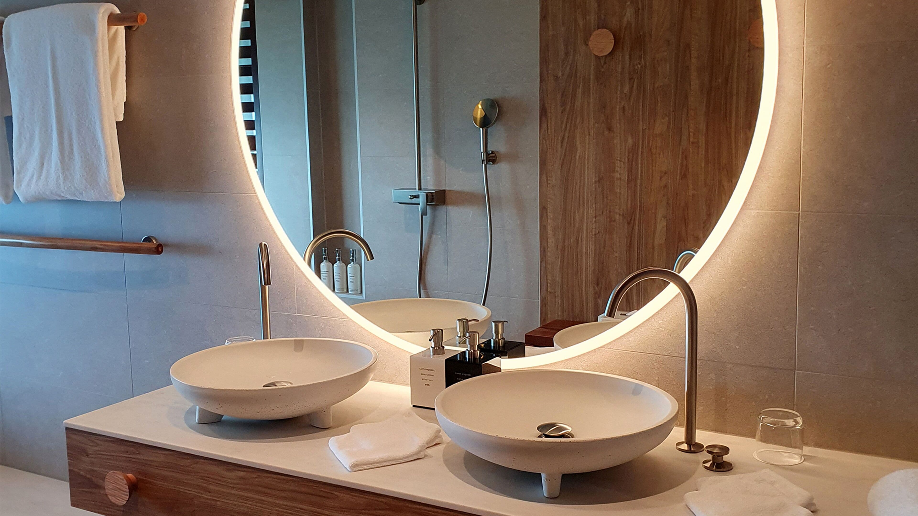 Un bagno con due lavabi a incasso, un mobile bagno in legno, un porta asciugamani e uno specchio con cornice in legno.