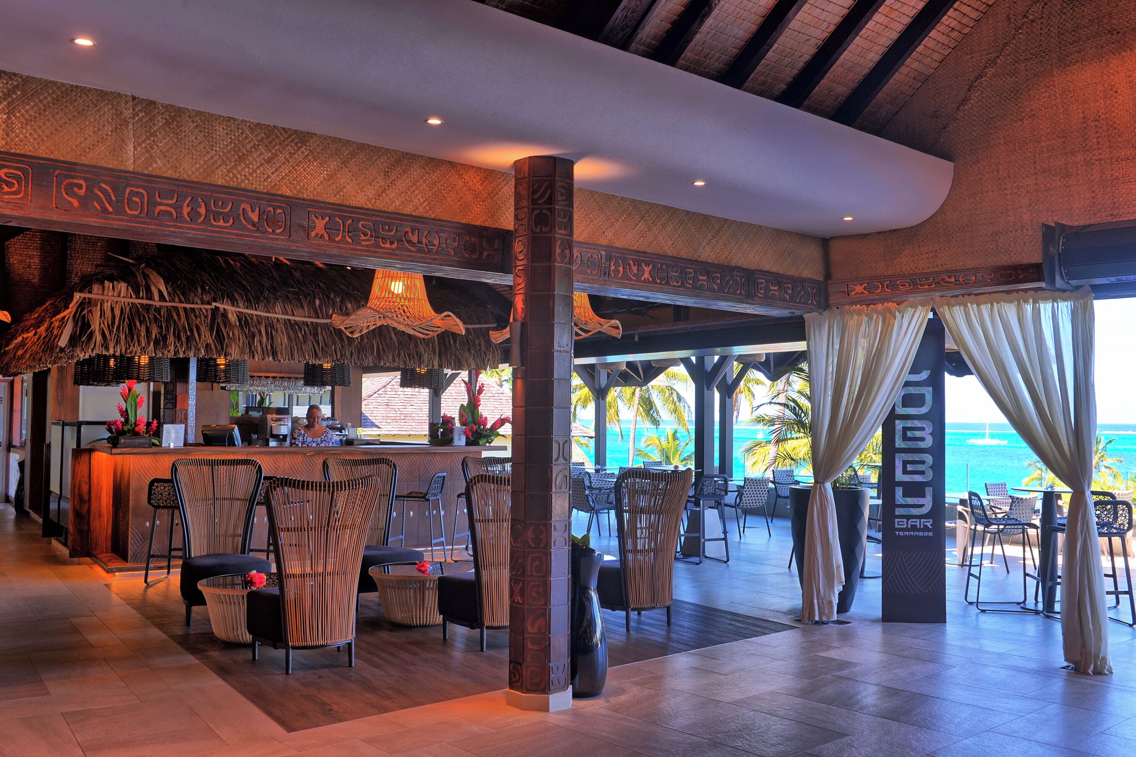 Zona de bar amb vista a l'oceà, amb decoració tropical i diferents disposicions de seients.