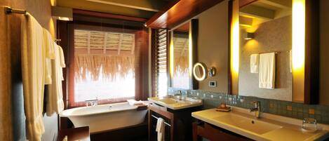 Un baño moderno con bañera, dos lavamanos y un espejo grande.