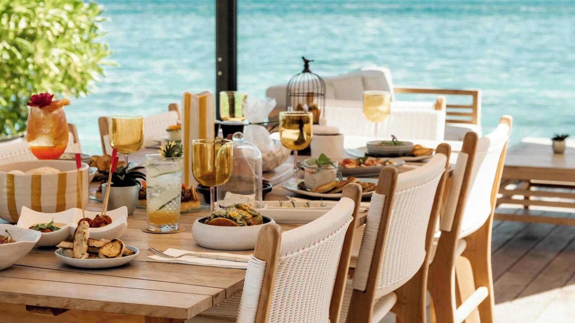 A dining table set with plates of food, glasses of wine, and a birdcage.