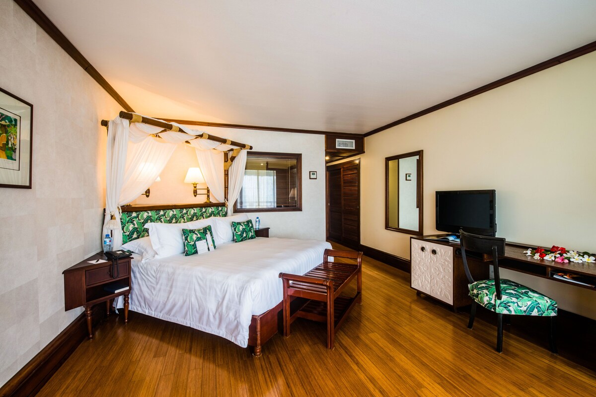 Une chambre d’hôtel avec un lit, une table de chevet, une lampe et un téléviseur.