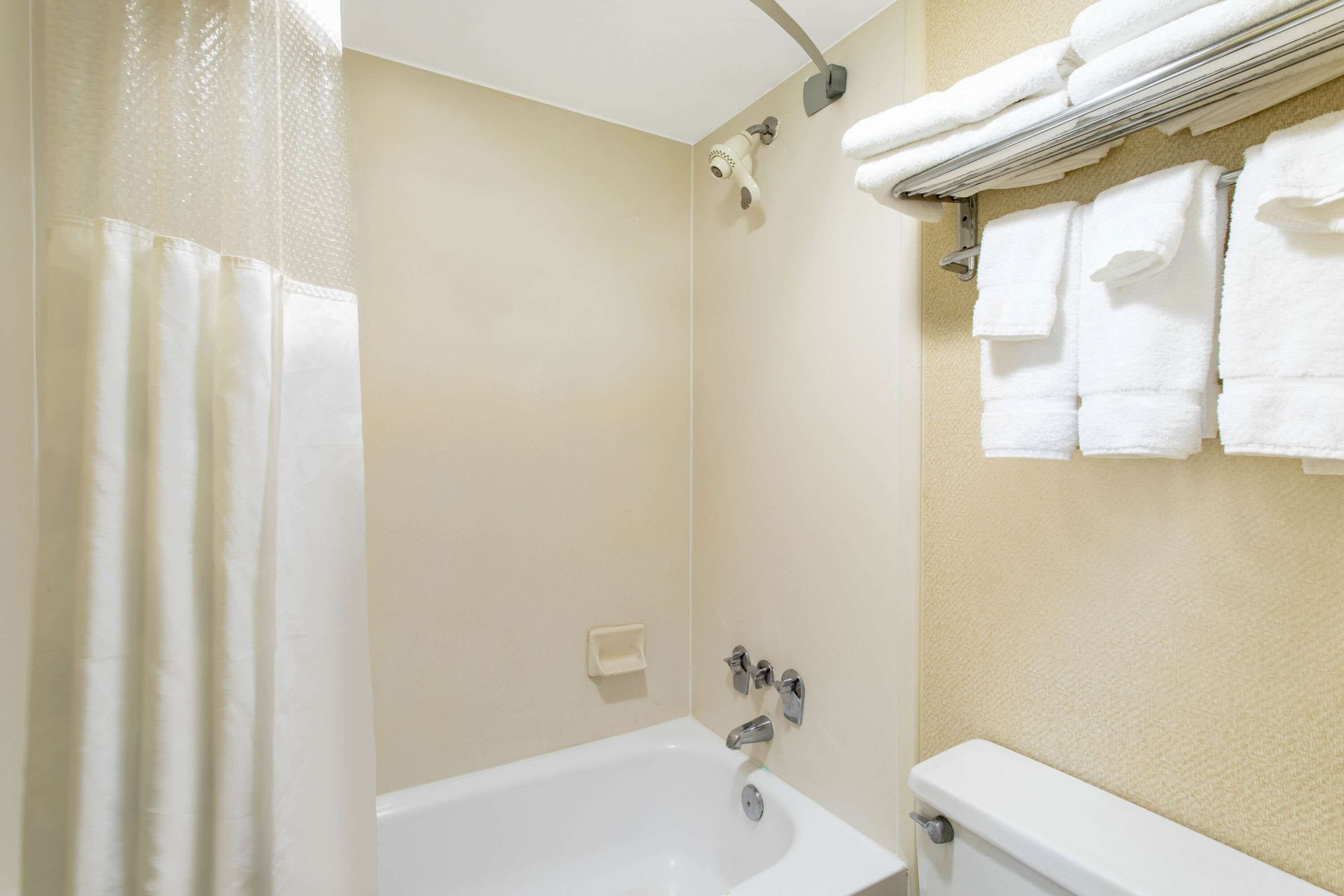 A bathroom with a bathtub, a shower, and a towel rack with folded towels.