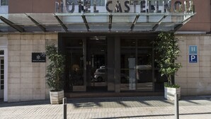 La entrada al Hotel Castellnou, con un toldo de cristal, plantas en macetas y un cartel de estacionamiento.