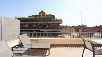 A rooftop terrace with outdoor seating and a view of a multi-story building.