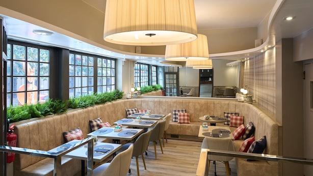 Un restaurante con una zona de estar curva, ventanas amplias e iluminación colgante.