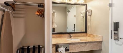 A bathroom with a sink, mirror, hairdryer, and towel rack.