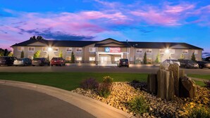 A hotel with a 'SureStay' sign, multiple parking spaces, and a landscaped area with rocks and plants.