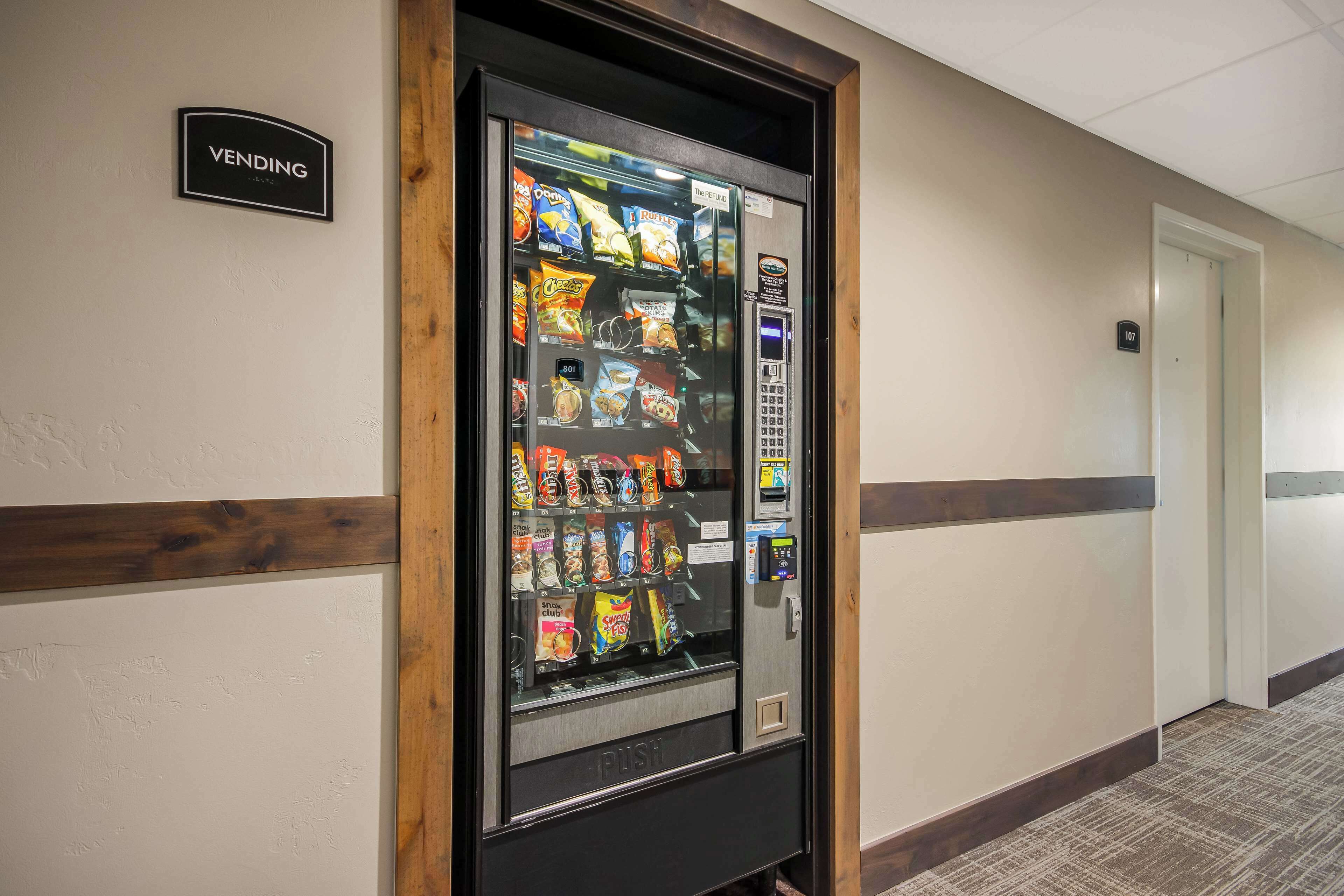 A vending machine in a hallway with a sign above it that reads "VENDING."