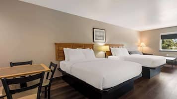 A hotel room with two beds, a wooden table, and chairs.