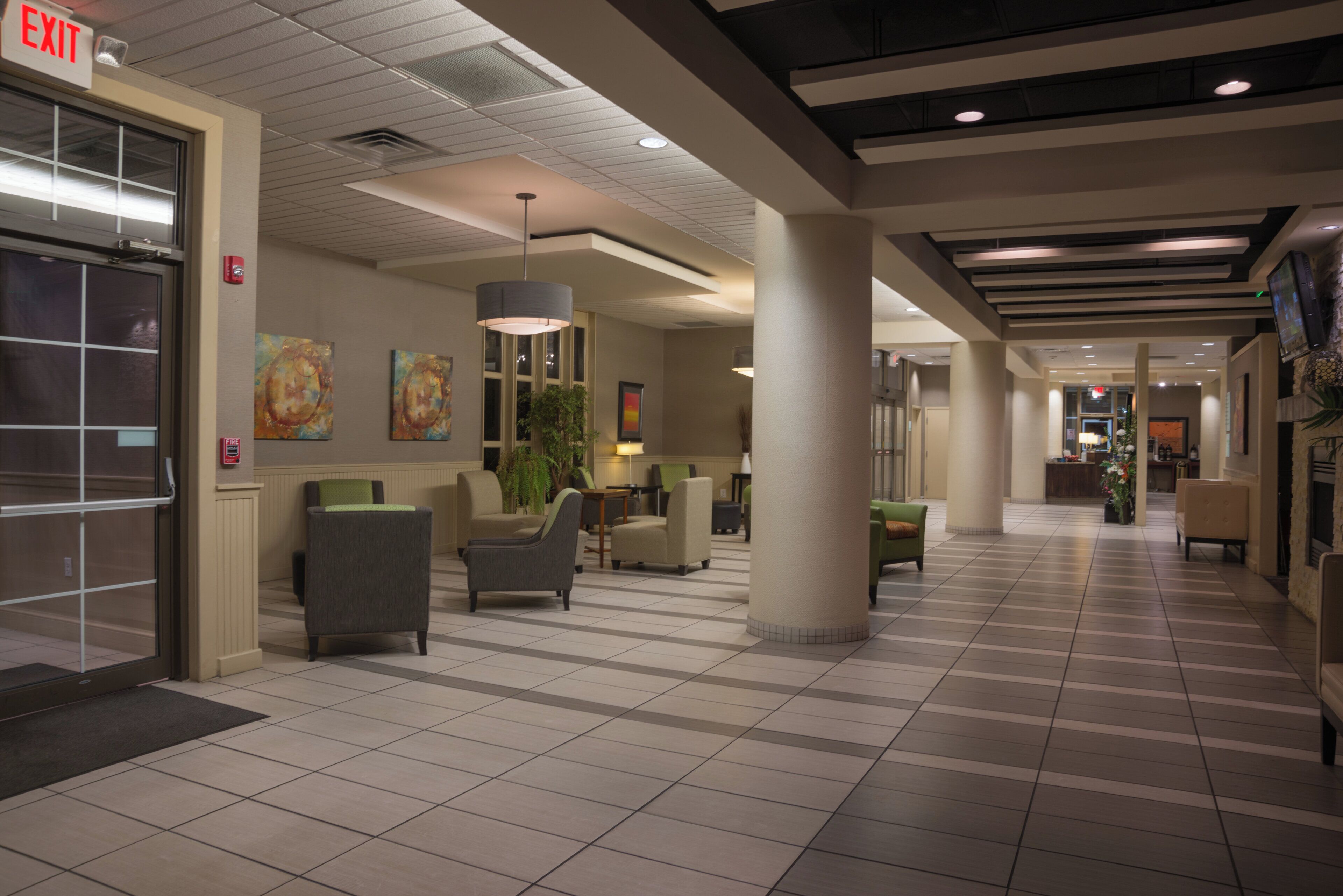 A hotel lobby with a reception desk, seating area, and an exit sign.