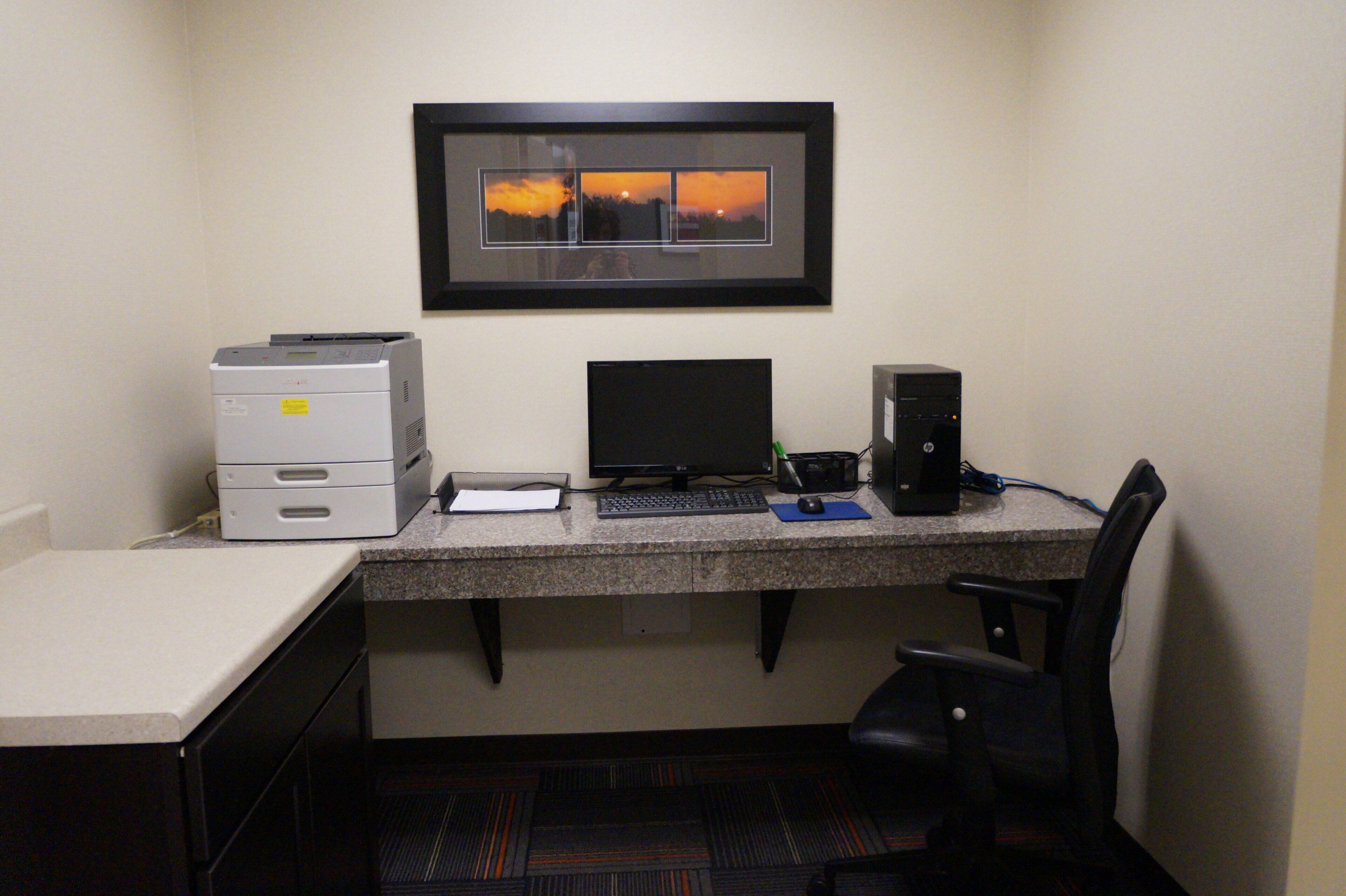 A small office space with a desk, printer, computer, and chair.