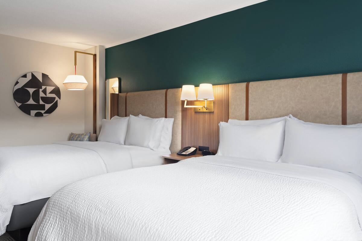 Ein Hotelzimmer mit zwei Betten, einem runden Wandbild und einem Nachttisch mit Telefon und Lampe.
