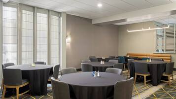 Un salón de conferencias con mesas redondas, sillas y un banco.