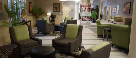 A hotel lobby with seating areas, a reception desk, and a large poster.
