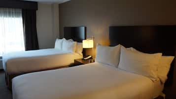 Ein Hotelzimmer mit zwei Betten, einem Nachttisch mit Lampe und einem Fenster mit Vorhängen.
