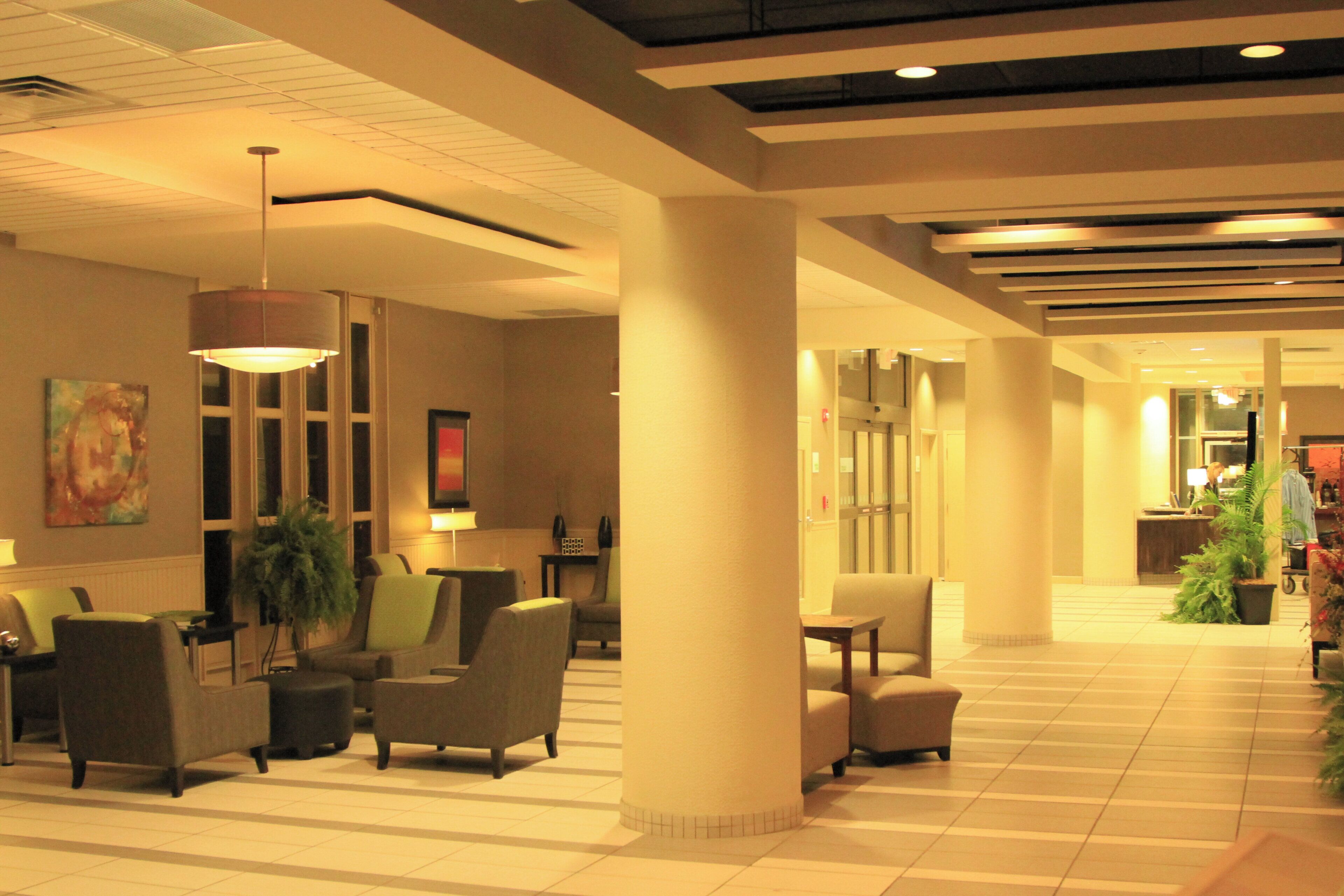 Un vestíbulo de hotel con mostrador de recepción, zona de estar y una columna grande.