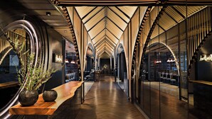 A modern interior with a wooden reception desk, arched ceiling, and seating area. - Bangkok Marriott Marquis Queen’s Park (Bangkok)