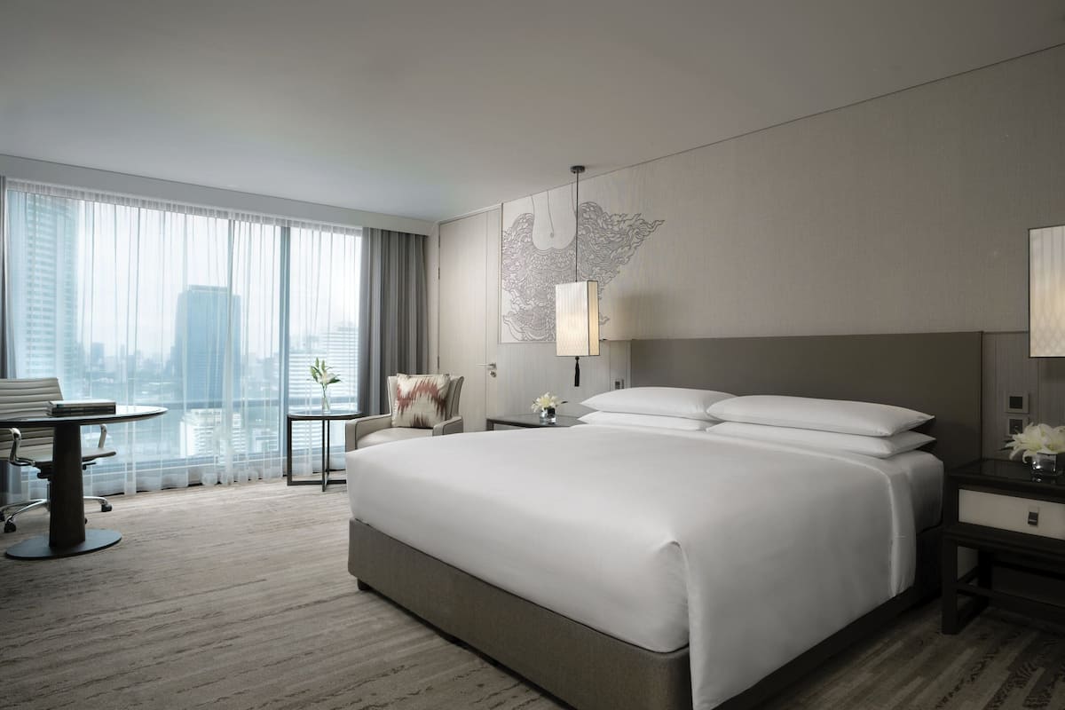 A modern hotel room with a large bed, a desk, and a chair.