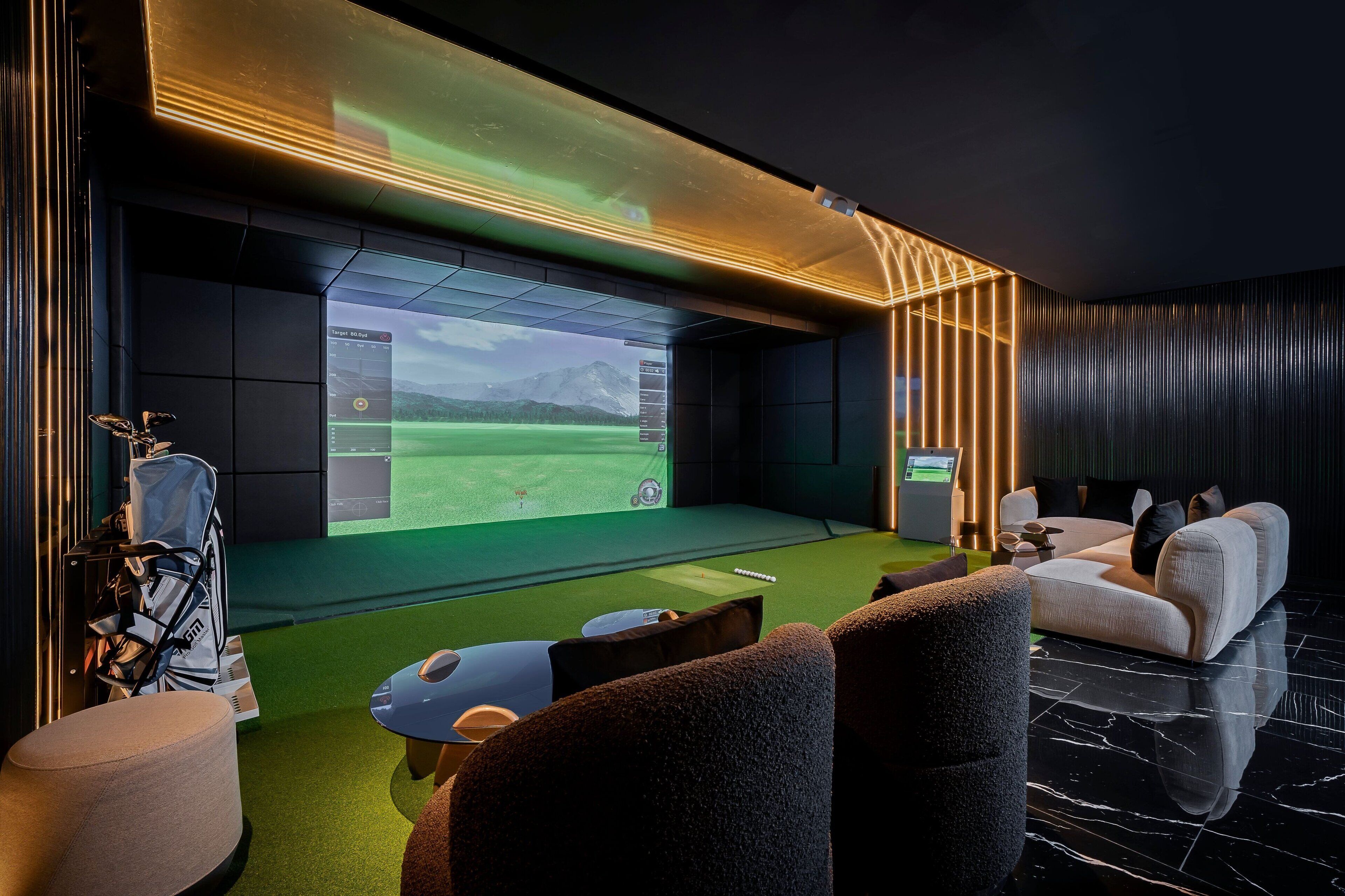Una habitación moderna con una gran pantalla mostrando una simulación de golf, asientos confortables y un diseño elegante.