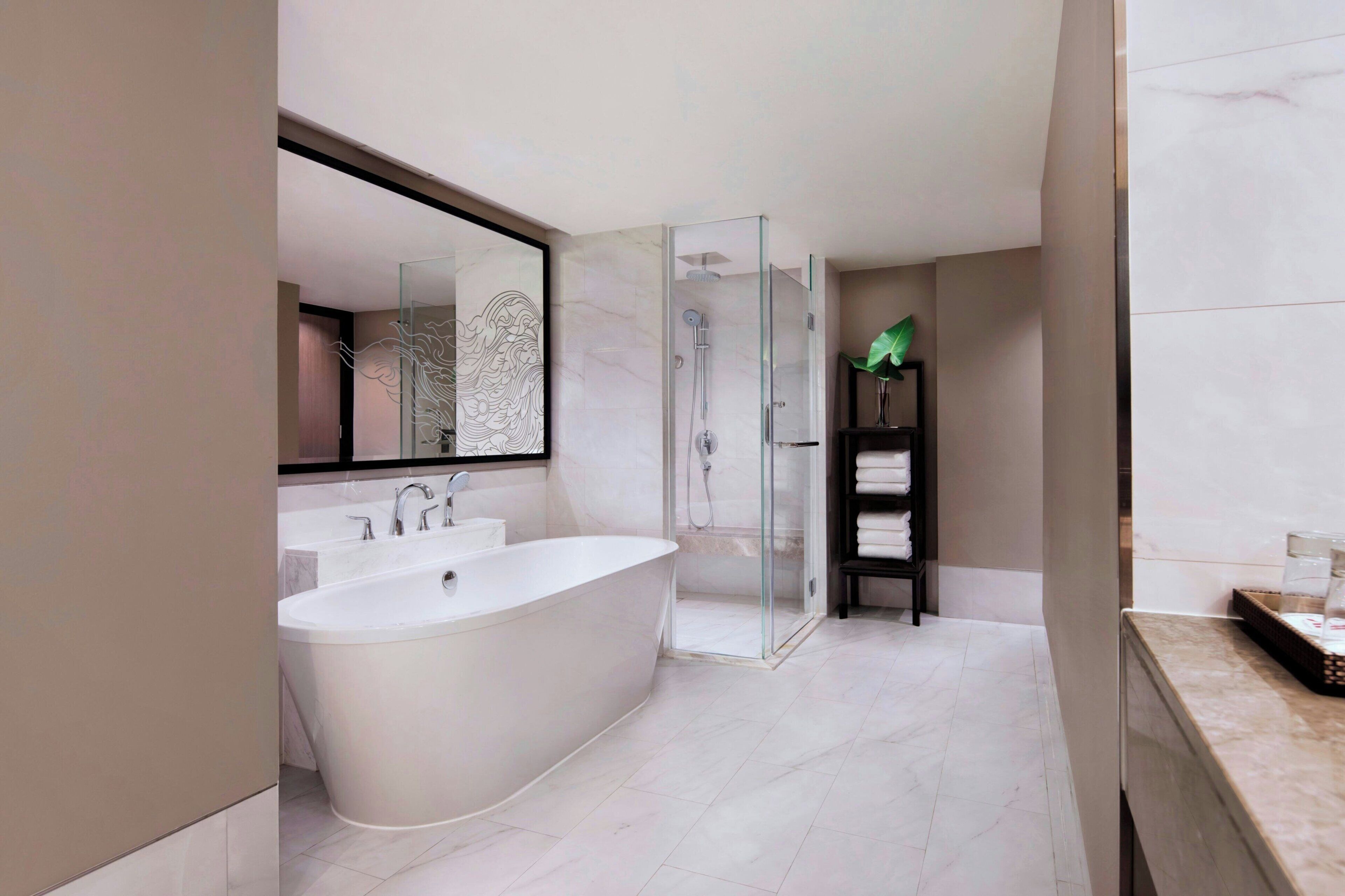 A modern bathroom with a freestanding bathtub, a glass-enclosed shower, and a large mirror.