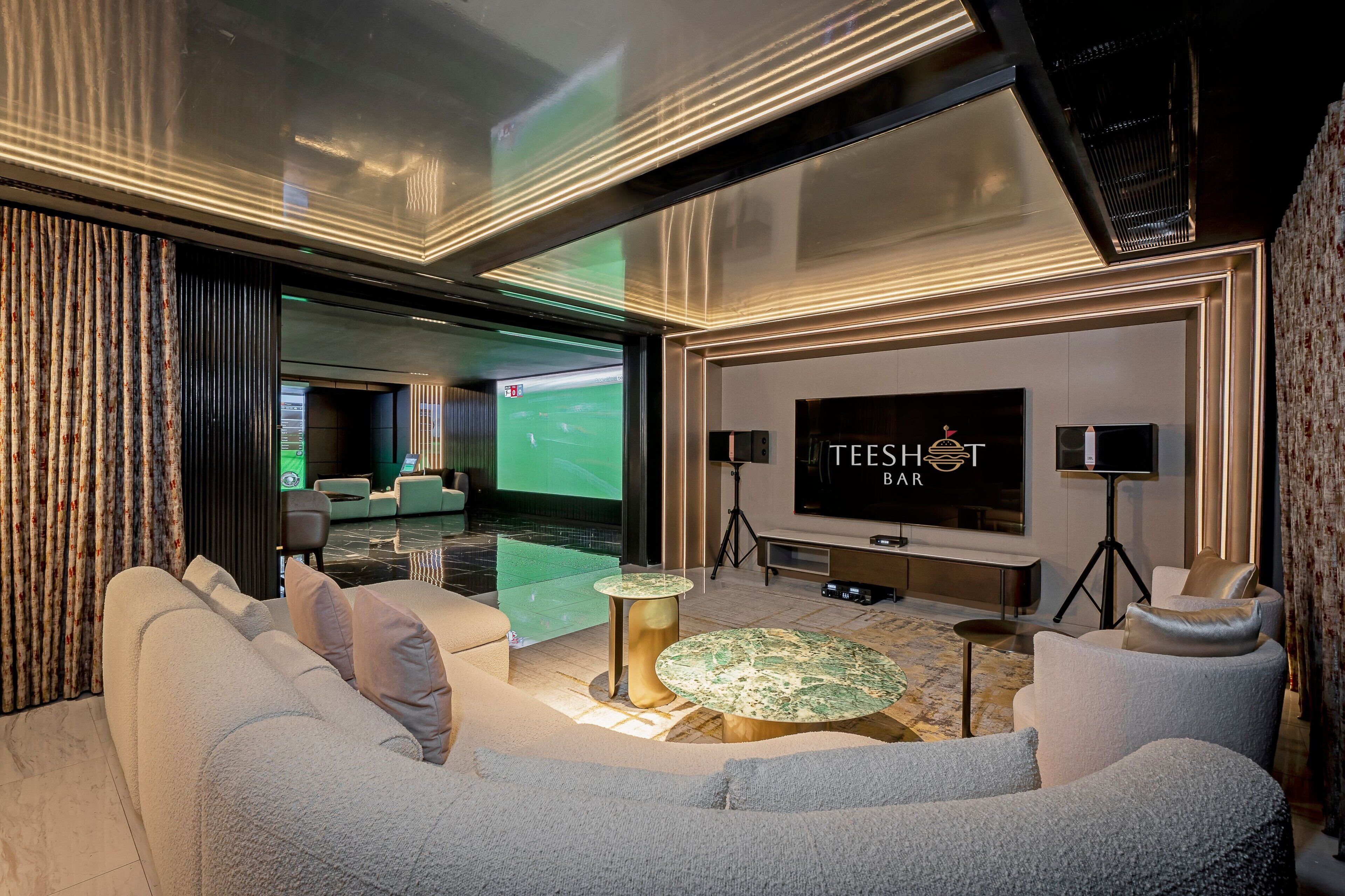 Una sala de estar moderna con un televisor grande, asientos cómodos y una zona de bar.
