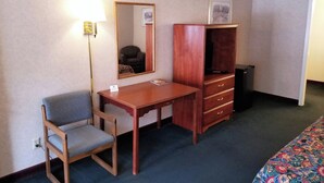 A hotel room with a wooden desk, a chair, a dresser, a mirror, and a bed with a patterned bedspread. - Keystone Boardwalk Inn and Suites (Keystone)