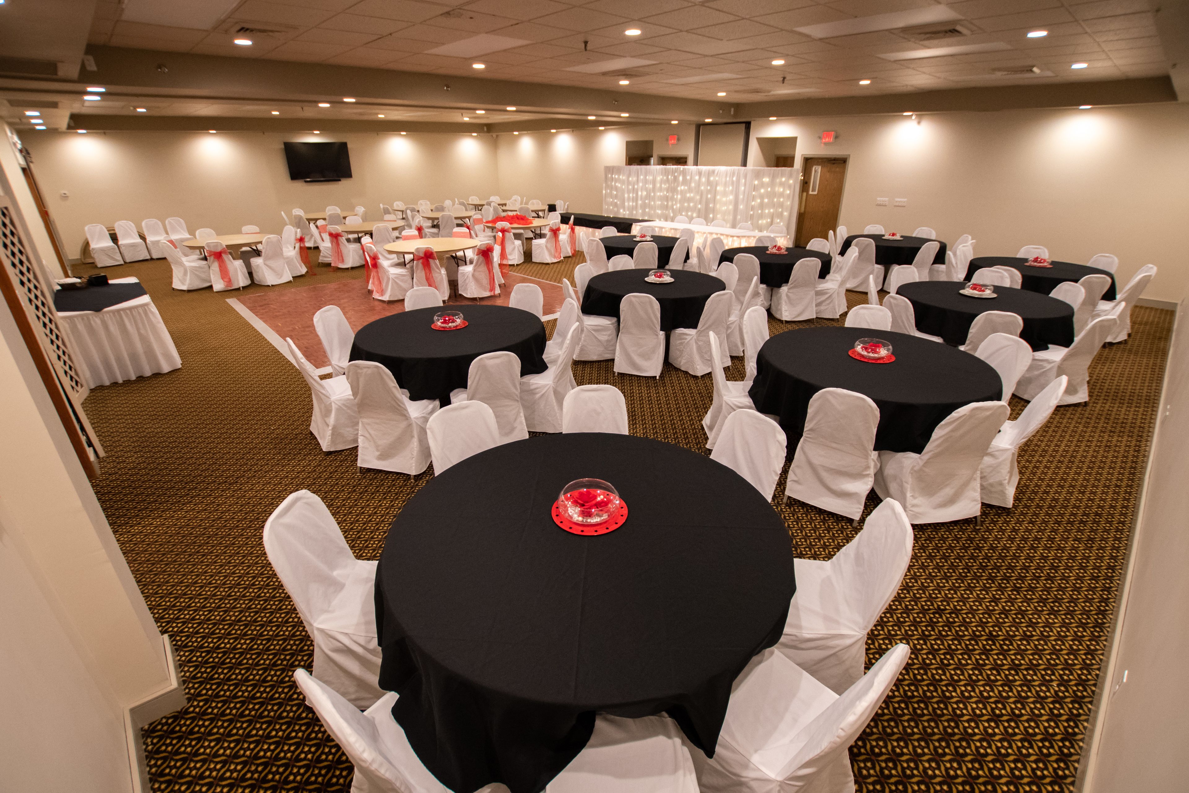 A conference room with multiple tables and chairs, arranged in rows.