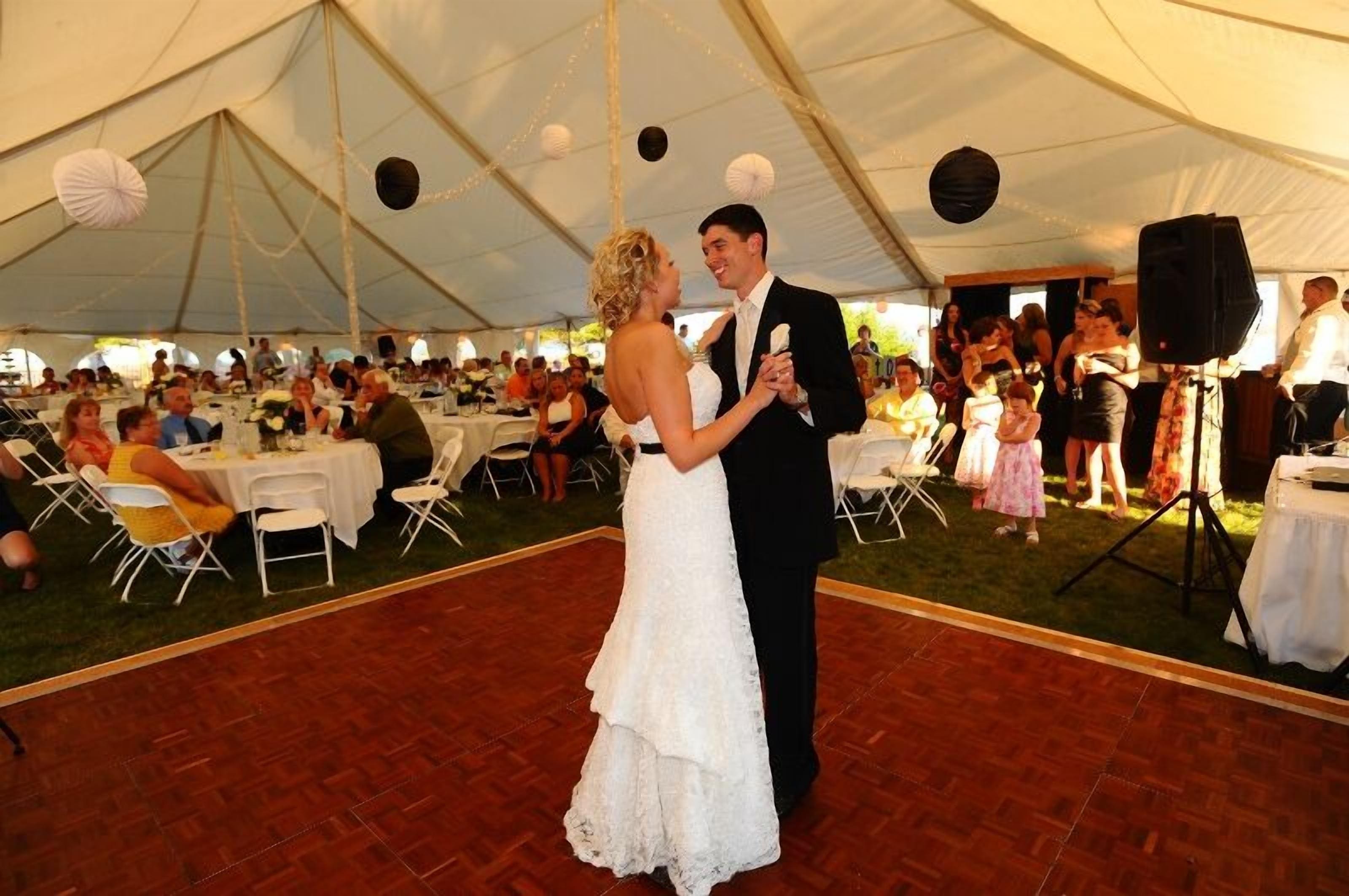 A tented wedding reception with tables and guests.