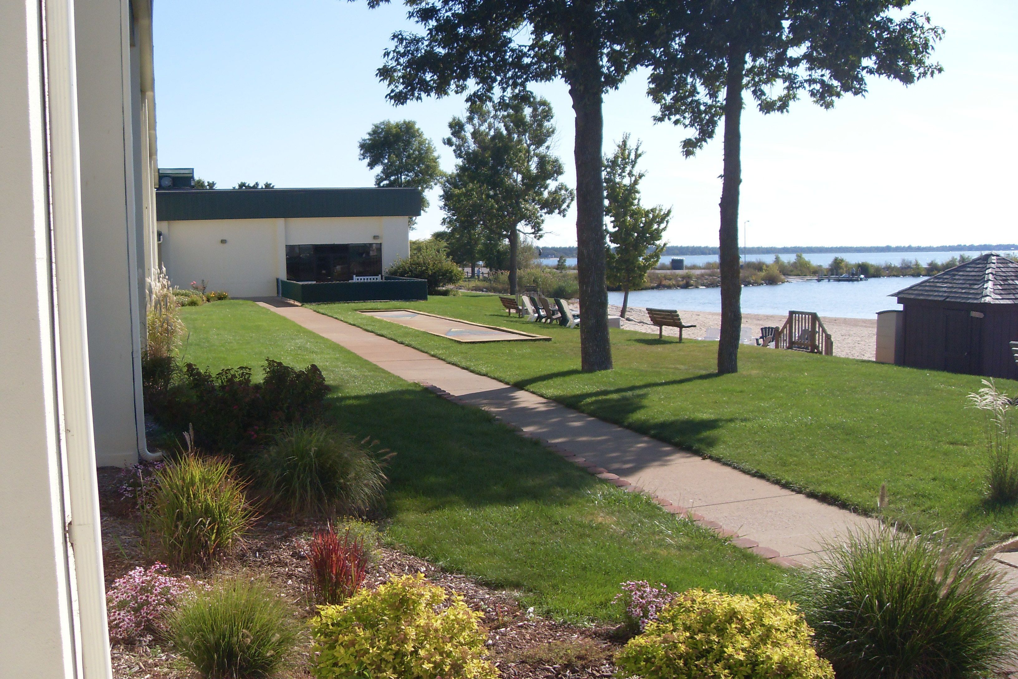 A well-maintained lawn with a pathway leading to a building, a dock by the water, and a boat house.