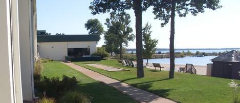 A well-maintained lawn with a pathway leading to a building, a dock by the water, and a boat house.