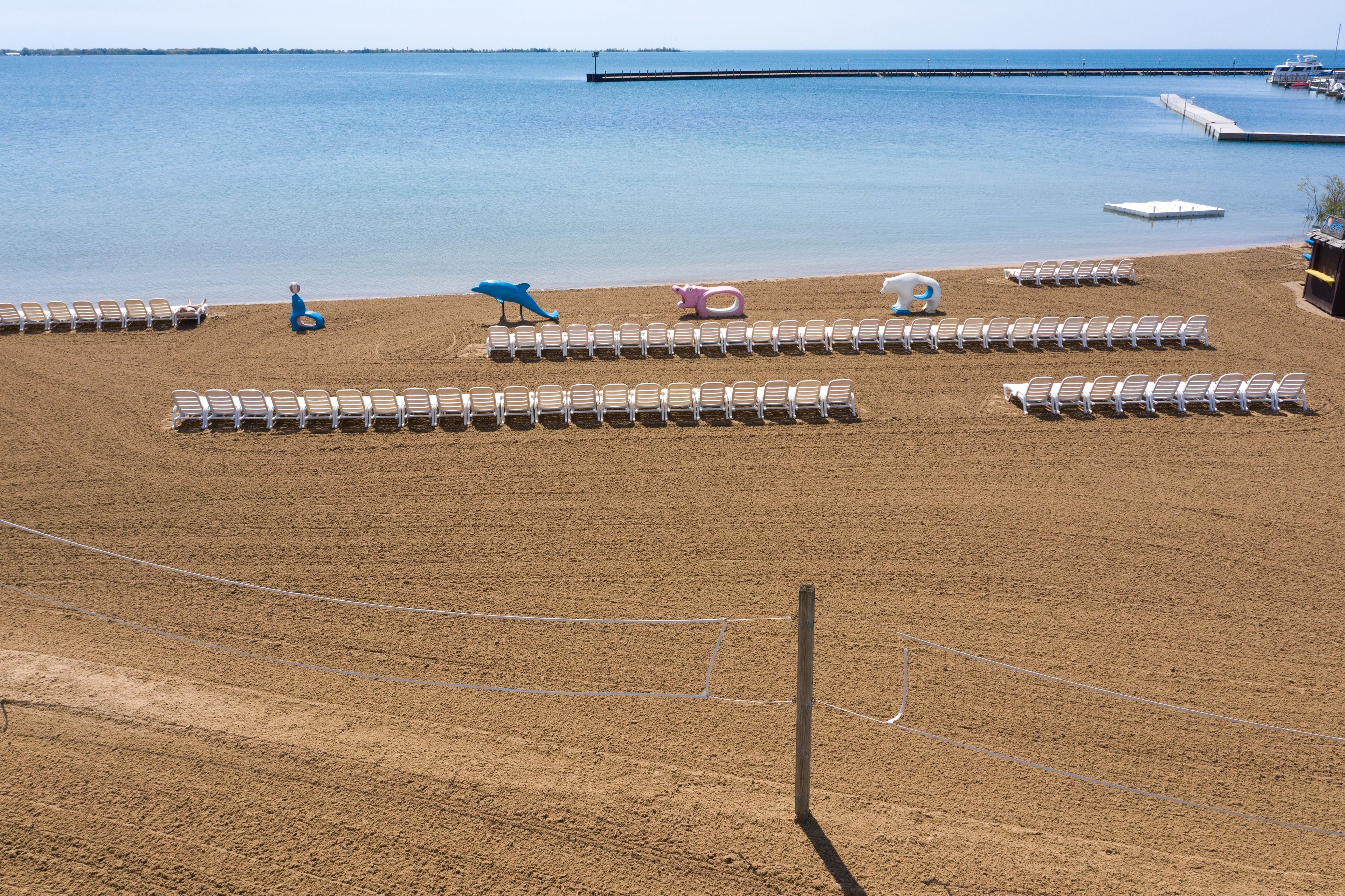 A beach with rows of sun loungers and a few colorful beach toys.