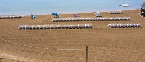 A beach with rows of sun loungers and a few colorful beach toys.