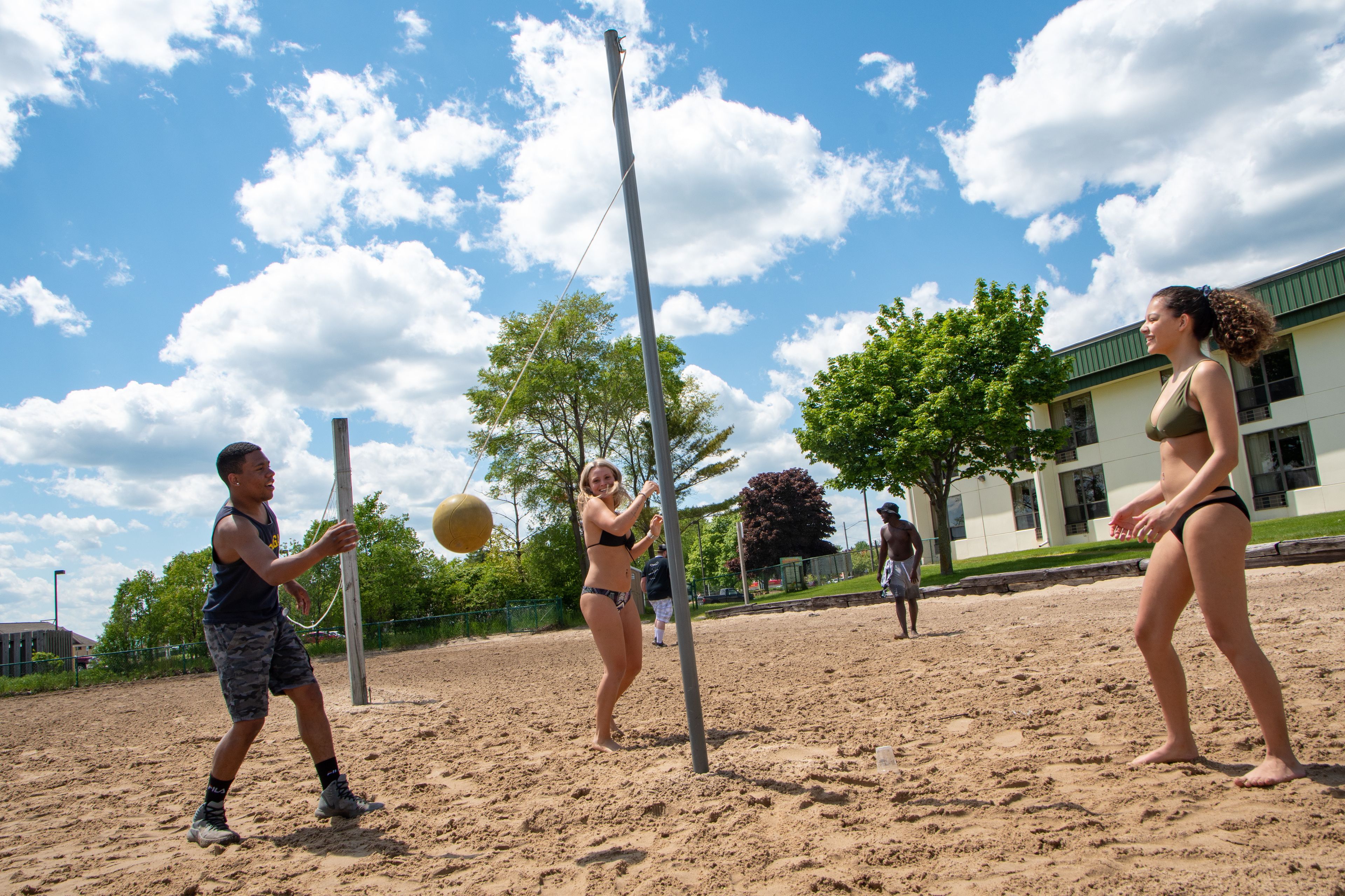 Un match de volleyball se déroulant sur un terrain de sable, avec un bâtiment en arrière-plan.
