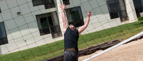 A volleyball player in mid-action, jumping to hit the ball over a net.