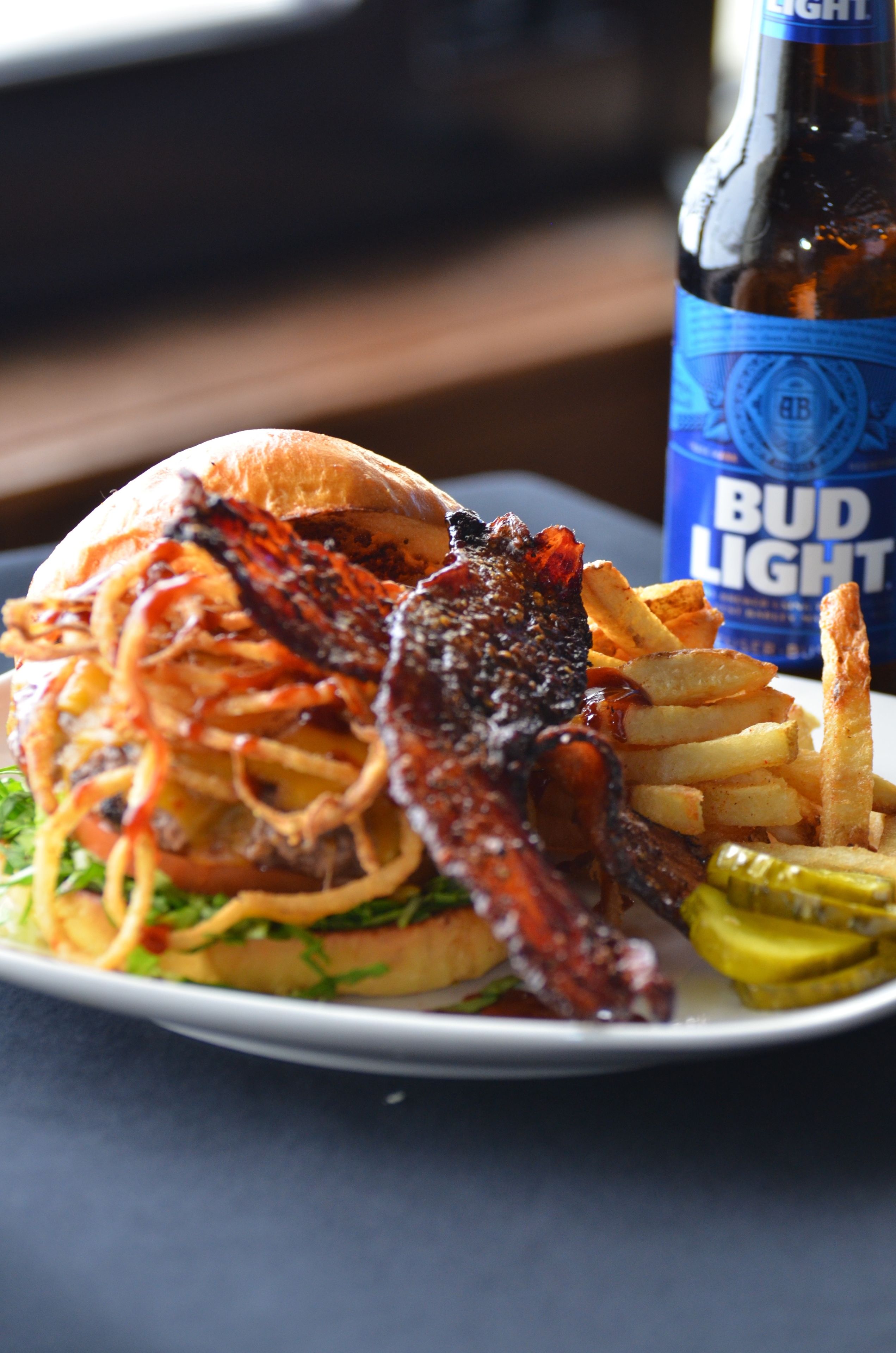 A burger with fries and a beer bottle.