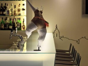 A bar area with a counter, bottles, and a decorative sculpture. - Mercure Porto Centro Santa Catarina (Porto)