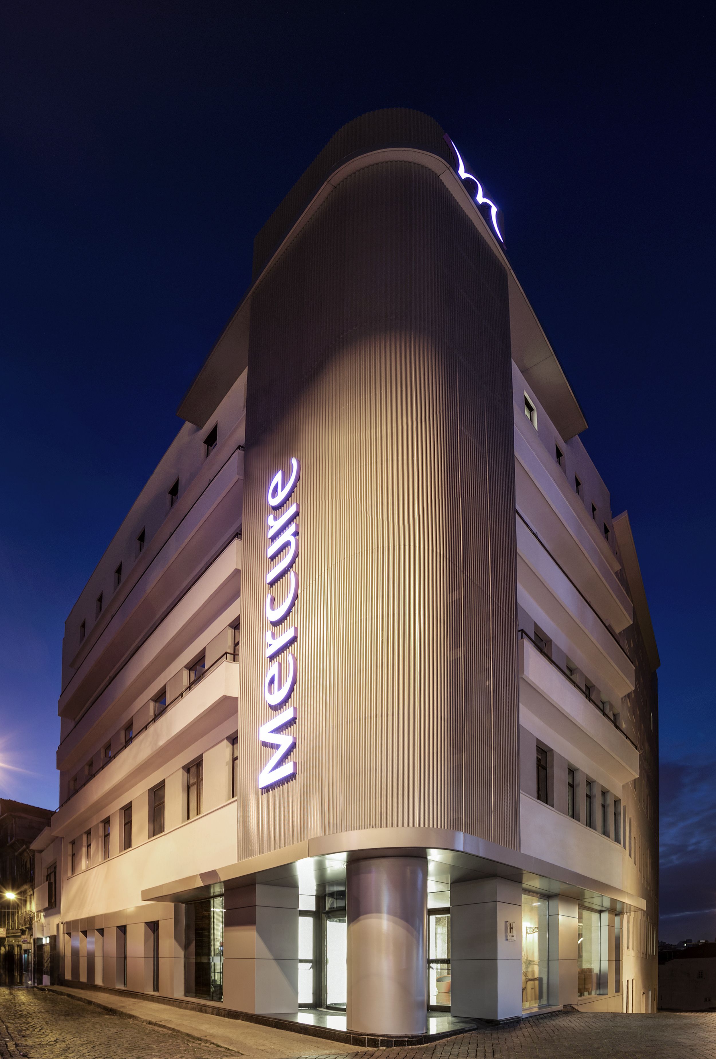 Un hotel moderno con fachada curva, varios balcones y un llamativo letrero de 'Mercure'.