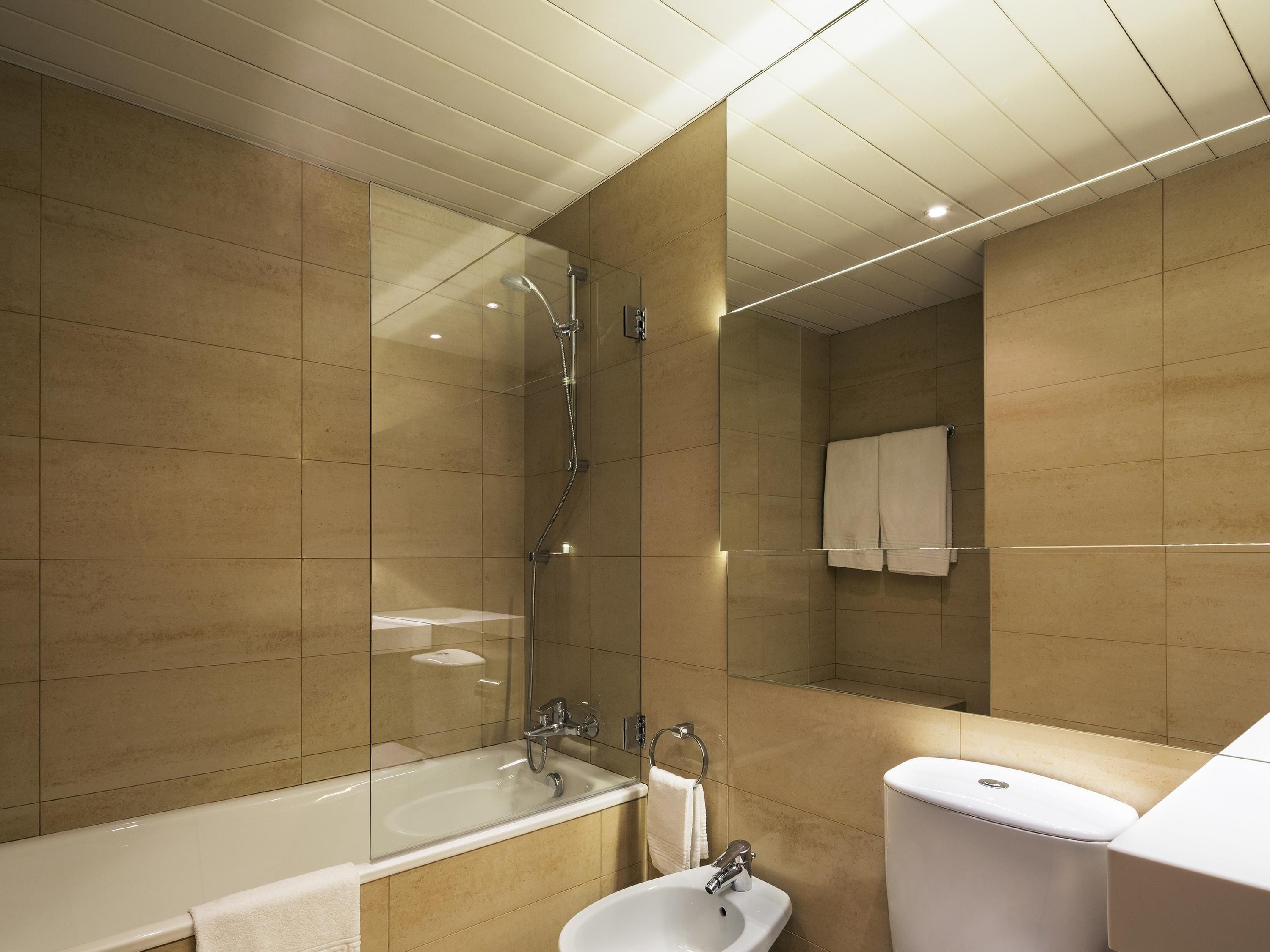 A modern bathroom with a glass-enclosed shower, a freestanding bathtub, a sink, and a toilet.