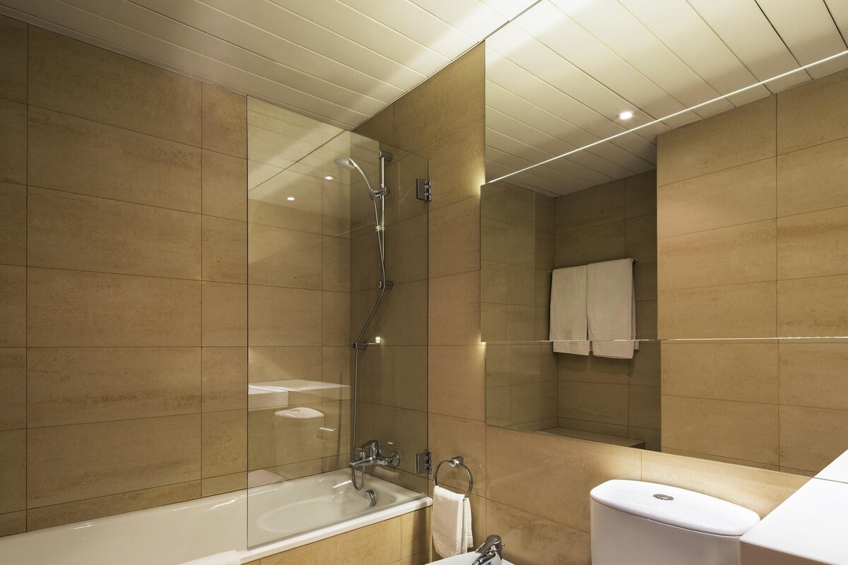 A modern bathroom with a glass-enclosed shower, a freestanding bathtub, a sink, and a toilet.