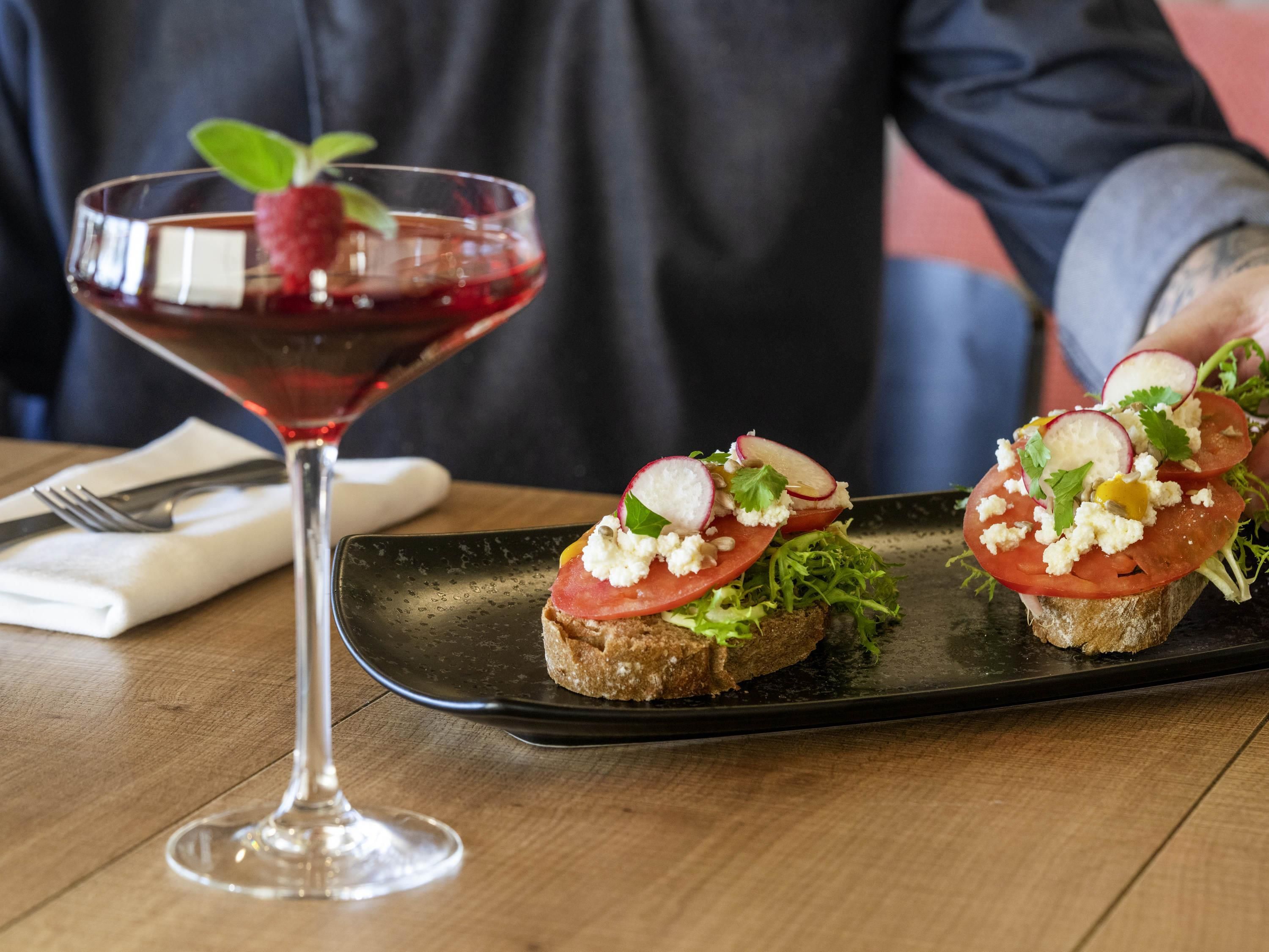 A martini glass with a garnish and a plate with two open-faced sandwiches.