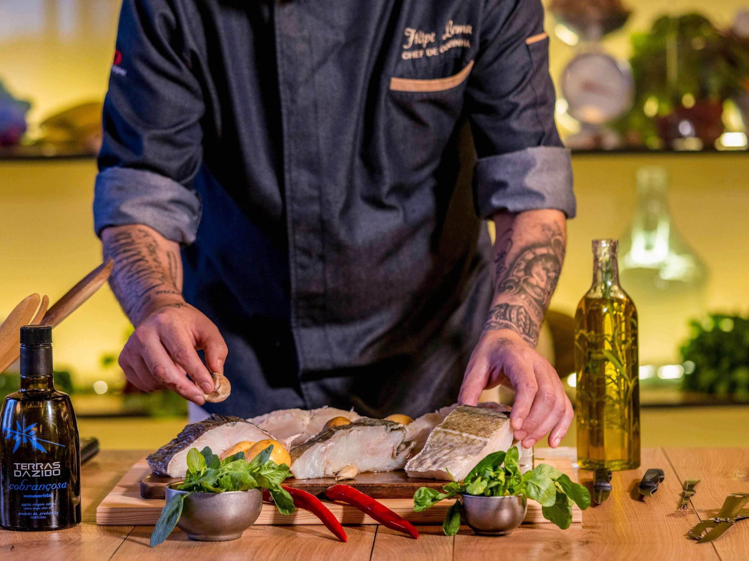 A chef preparing fish with herbs and spices on a wooden board.