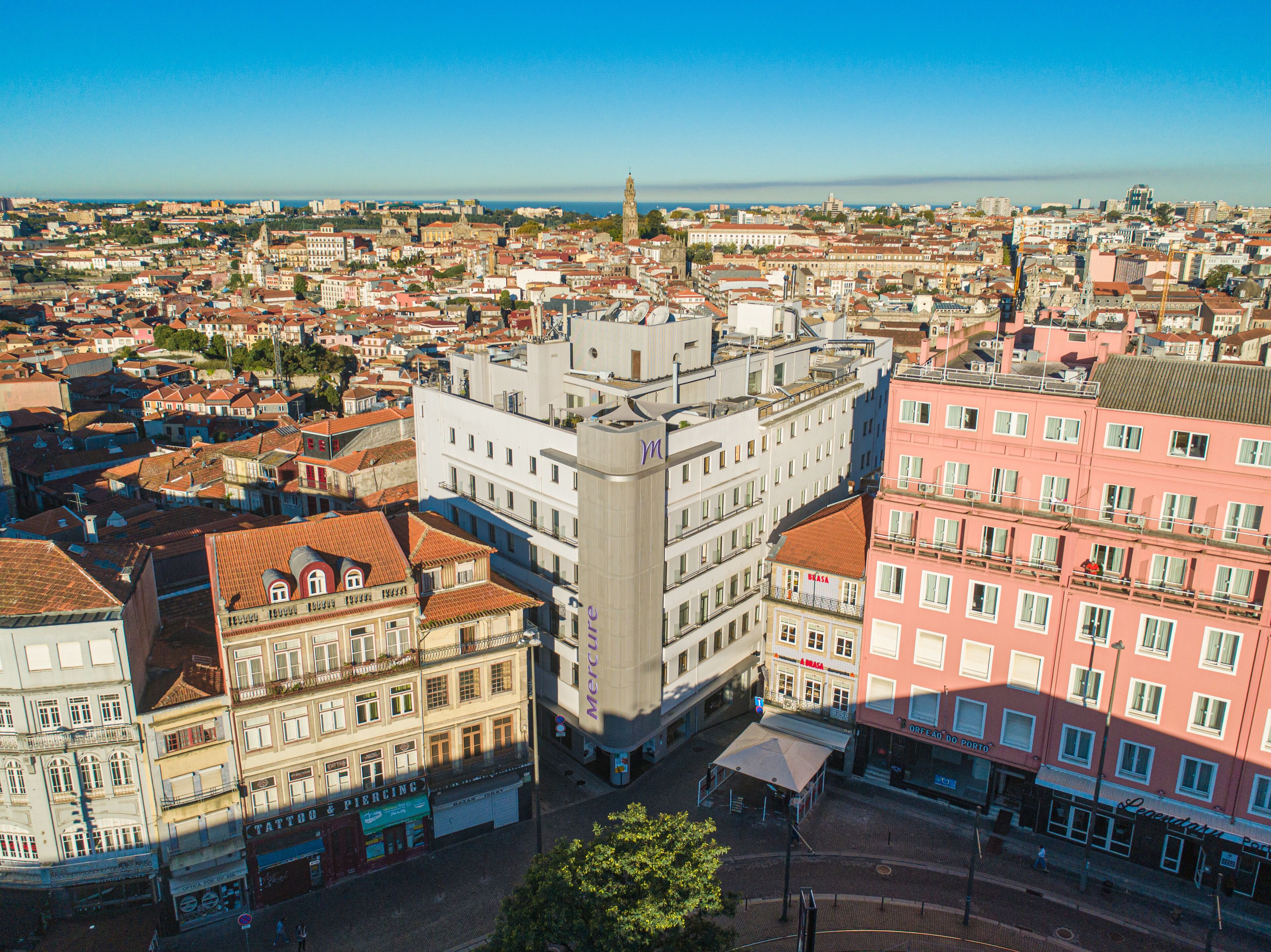 Un paisaje urbano con un edificio destacado que presenta una torre, rodeado de otros edificios con diversos estilos arquitectónicos.