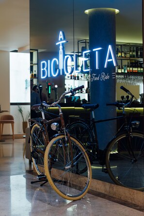 A bicycle parked in front of a bar named "BICICLETA Food Ride" with a neon sign. - Mercure Porto Centro Santa Catarina (Porto)