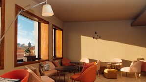 A modern living room with a large window, wooden flooring, and contemporary furniture. - Mercure Porto Centro Santa Catarina (Porto)