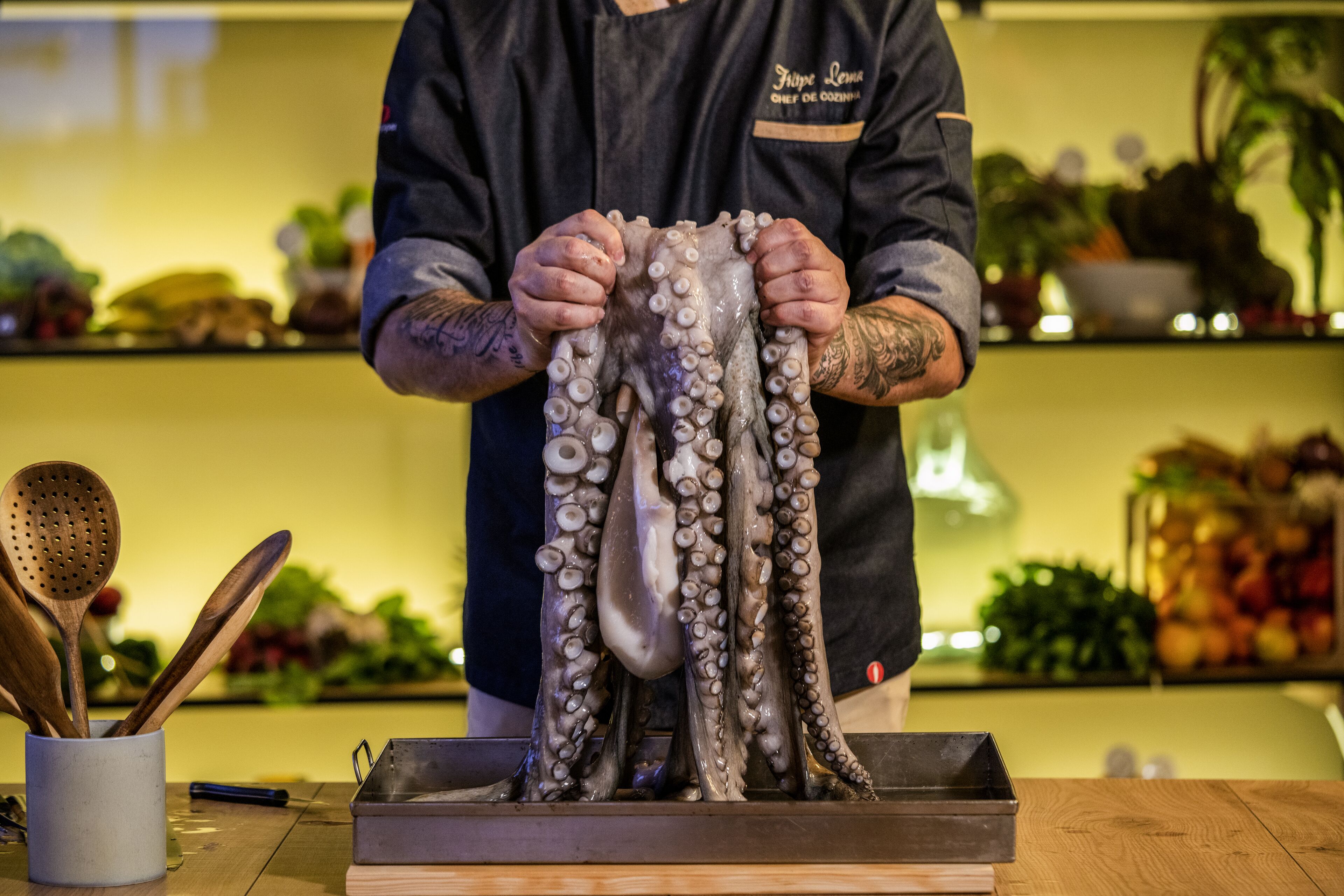 A person holding a large octopus in a kitchen setting.