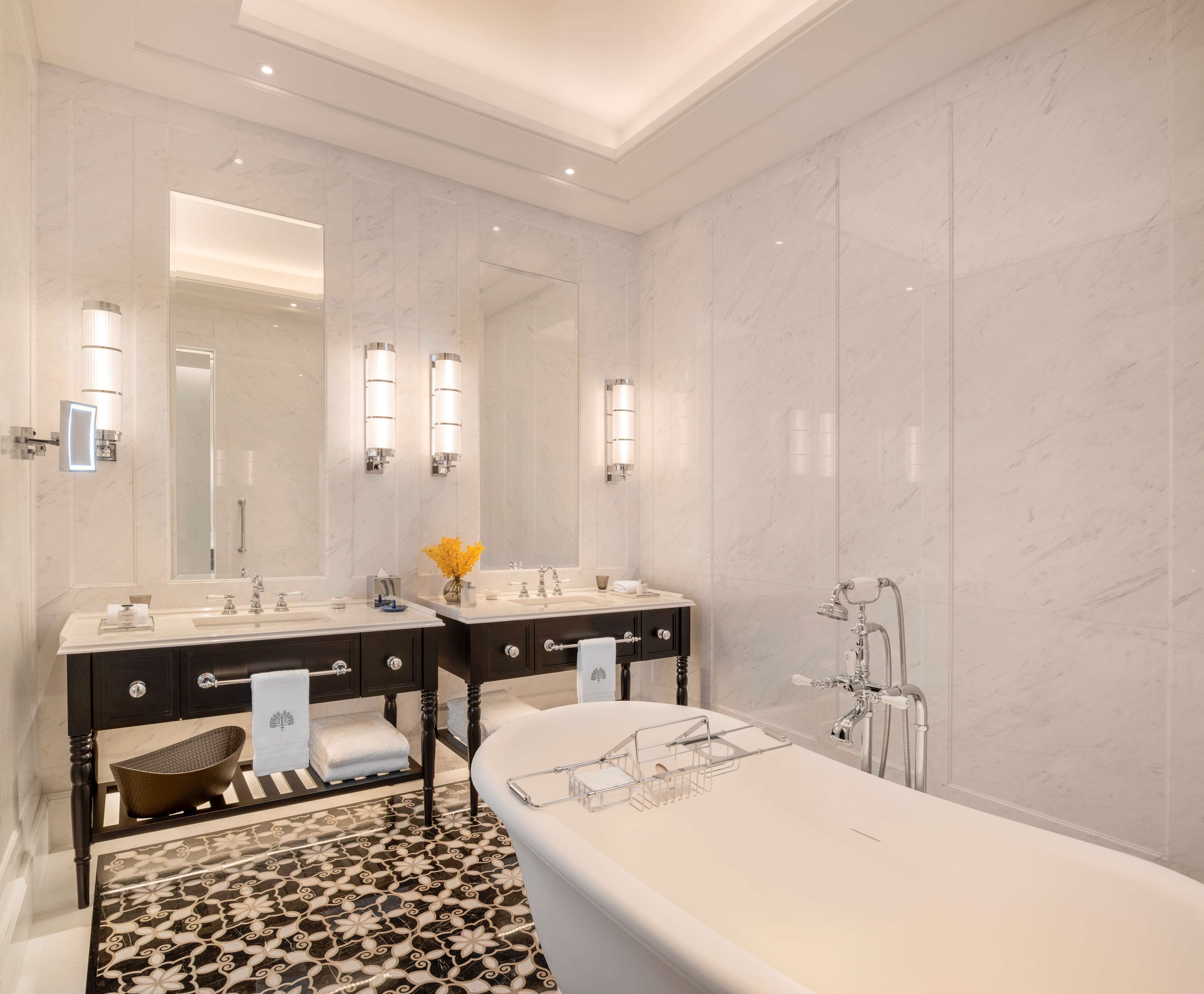 A modern bathroom with two sinks, a large mirror, and a bathtub.
