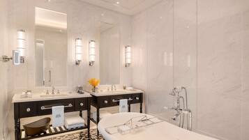 A modern bathroom with two sinks, a large mirror, and a bathtub.