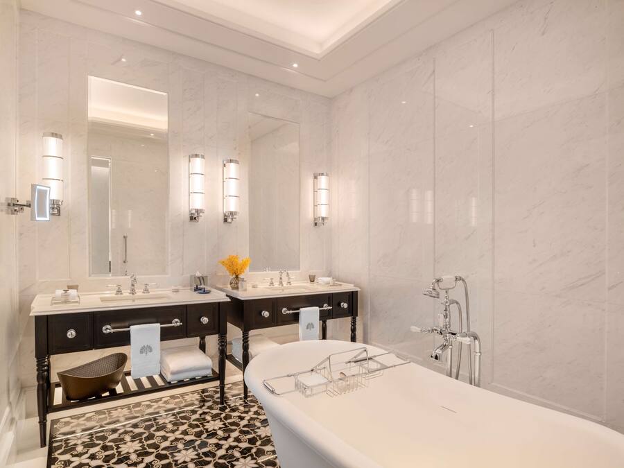 A modern bathroom with two sinks, a large mirror, and a bathtub.