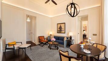 A modern living room with a sofa, two armchairs, a coffee table, and a dining table set with fruit.
