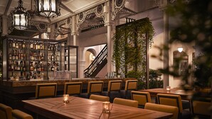 Un espace bar avec des étagères remplies de bouteilles, un escalier et un coin repas avec des tables et des chaises.